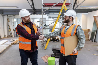 Junge Ingenieure schütteln sich auf der Baustelle die Hände - WPEF06941