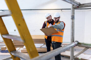 Engineers wearing hardhat having discussion over document - WPEF06947
