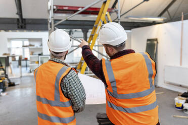 Engineers wearing hardhat examining and having discussion at site - WPEF06949