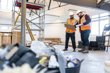 Junge Ingenieure diskutieren auf einer Baustelle über ein Dokument - WPEF06956