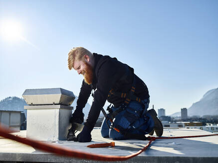 Dachdecker repariert Dach an einem sonnigen Tag - CVF02196