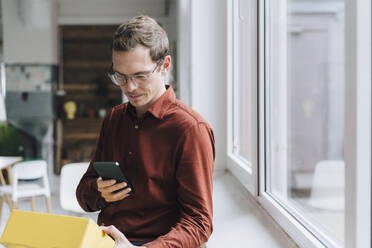 Geschäftsmann scannt gelben Kasten durch Smartphone im Büro - JOSEF15785