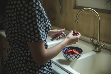 Hände einer Frau beim Schneiden frischer Erdbeeren in der Küche - PCLF00209