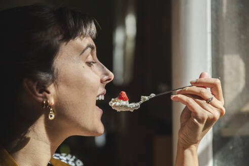 Junge Frau isst Löffel mit Erdbeeren und Sahne - PCLF00214