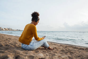 Frau mit Smartphone am Strand sitzend - JOSEF15860
