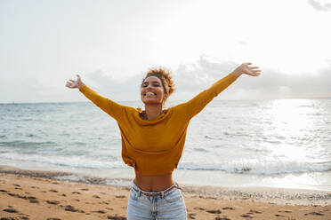 Happy woman with arms outstretched enjoying at beach - JOSEF15865