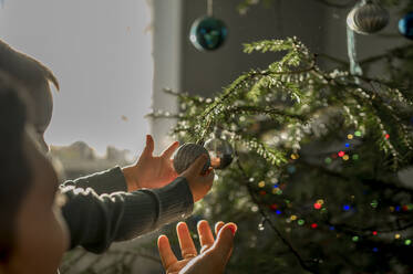Vater und Sohn schmücken den Weihnachtsbaum zu Hause - ANAF00908