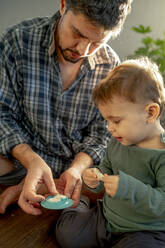 Father and son playing with clay at home - ANAF00913