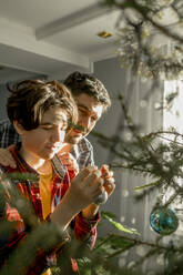 Father and son decorating Christmas tree at home - ANAF00914