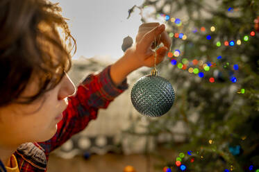 Boy decorating Christmas tree at home - ANAF00916