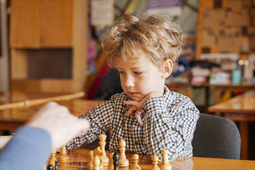 Junge mit Hand am Kinn beim Schachspielen im Sportverein - OSF01336