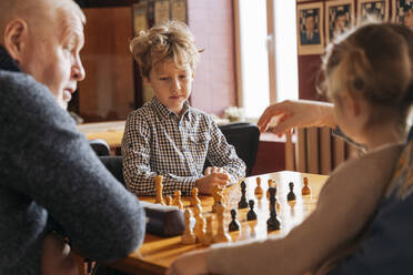 Kids playing chess with grandfather at country club - OSF01337