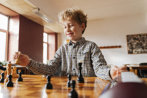 Lächelnder Junge hat Spaß beim Schachspielen im Club - OSF01338