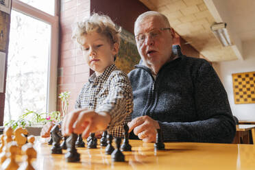 Son playing chess with grandfather at club - OSF01342