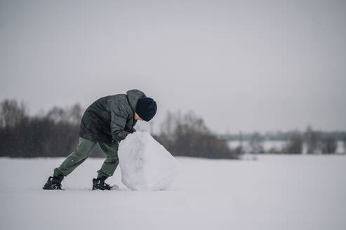 Junge modelliert großen Schneeklumpen - ANAF00917