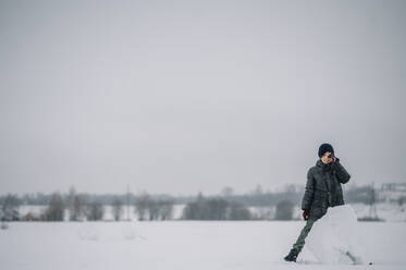 Boy standing by big lump of snow - ANAF00918