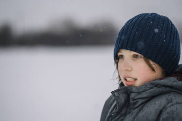 Cute boy wearing knit hat standing in snow - ANAF00921