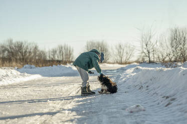 Boy playing with dog on snow - ANAF00925