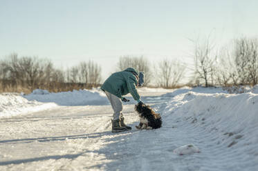 Junge spielt mit Hund im Schnee - ANAF00925