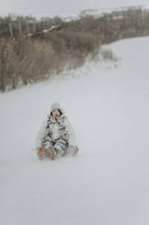 Fröhliches Teenager-Mädchen fährt aufblasbaren Schlitten im Schnee - ANAF00933