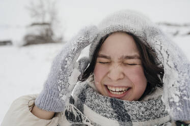 Fröhliches Teenager-Mädchen mit Strickmütze, das sich im Winter vergnügt - ANAF00942