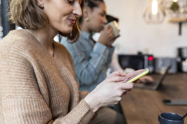 Lächelnde Geschäftsfrau mit Smartphone im Büro - WPEF06967