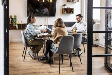 Geschäftskollegen sitzen mit Tabellen und diskutieren am Tisch im Büro - WPEF07008