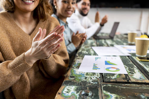 Geschäftsleute applaudieren mit Tabellen auf dem Tisch im Büro - WPEF07020