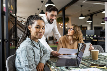 Smiling businesswoman with coworkers sitting in meeting room at office - WPEF07024