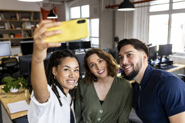 Glückliche Geschäftskollegen machen ein Selfie mit ihrem Handy im Büro - WPEF07048