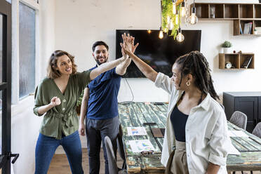 Glückliche Geschäftsfrau mit Kollegen, die im Büro High Five machen - WPEF07050