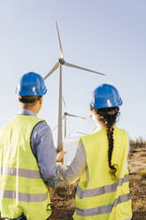 Ingenieure diskutieren an einem sonnigen Tag über Windkraftanlagen - MGRF00861