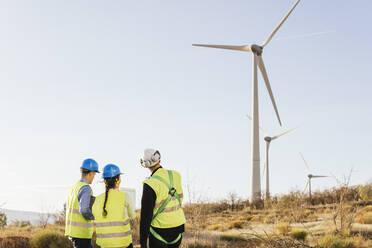 Technician discussing with engineers over wind turbines - MGRF00864