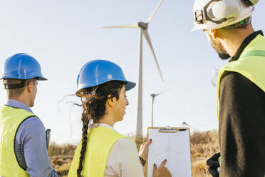 Engineers discussing with technician over wind turbine diagram - MGRF00865