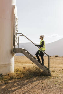 Technician standing at entrance of wind turbine - MGRF00881