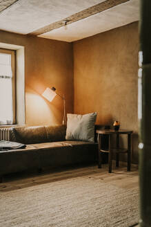 Sofa und beleuchtete Lampe im Wohnzimmer - MJRF00904