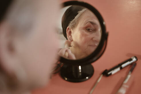 Senior woman looking in mirror doing make up at home - NGF00783