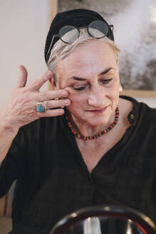 Senior woman massaging face at home - NGF00786