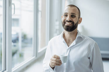 Glücklicher Geschäftsmann mit einer Tasse Kaffee im Büro zu Hause - JOSEF15956