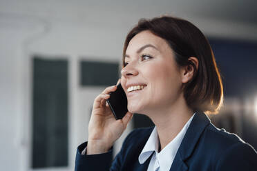 Happy businesswoman talking through smart phone in office - JOSEF16000