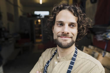 Thoughtful young businessman with curly hair in storage room - JOSEF16135