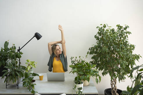 Freelancer stretching arms at desk - SVKF01132