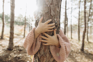 Mädchen umarmt Baumstamm im Wald - SIF00661