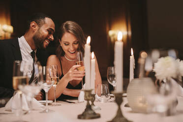 Junges Paar sitzt am Esstisch mit Kerzen und trinkt Wein. Liebender Mann und Frau bei einer Gala-Dinner-Party. - JLPSF29019
