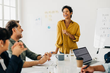 Professional business woman having a meeting with her colleagues in an office. Business woman doing a presentation in a boardroom. Happy black woman leading a team discussion. - JLPSF29043