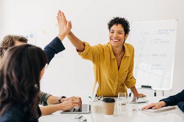 Erfolgreiche Frauen geben sich in einer Besprechung ein High Five. Glückliche Geschäftsleute, die ein erreichtes Ziel feiern. Eine Gruppe von Geschäftsleuten, die in einem Büro zusammenarbeiten. - JLPSF29063