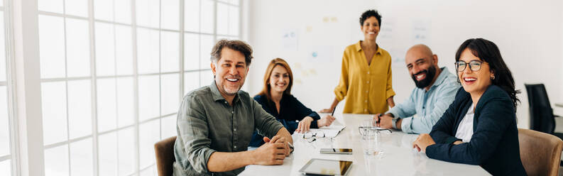 Ein Team erfolgreicher Geschäftsleute sitzt in einem Sitzungssaal. Eine Gruppe verschiedener Fachleute lächelt in die Kamera. Kreative Geschäftsleute bei einer Besprechung in einem Büro. - JLPSF29070