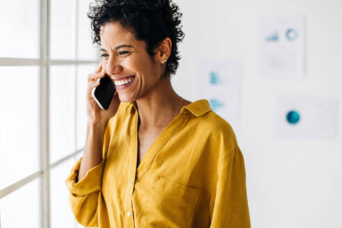 Geschäftsfrau telefoniert in einem Büro. Professionelle Frau lächelt, während sie mit Kunden am Telefon spricht, es gelingt ihr, nützliche Geschäftskontakte für ihr Unternehmen herzustellen. - JLPSF29099