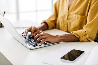 Geschäftsfrau, die an einem Laptop an ihrem Bürotisch arbeitet. Weibliche Fachkraft, die mit ihren Kunden in einem Technologieunternehmen kommuniziert. - JLPSF29117