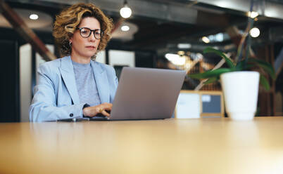 Geschäftsfrau, die an einem Laptop in einem Coworking-Büro arbeitet. Reife Geschäftsfrau, die online an einem Projekt arbeitet. Berufstätige Frau, die aus der Ferne arbeitet. - JLPSF29123